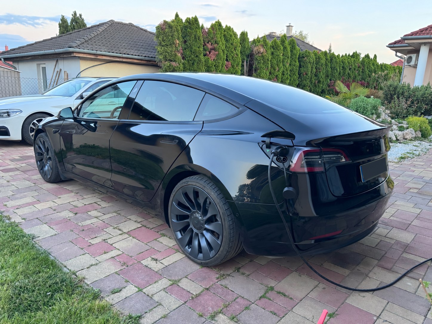 Fekete Tesla Model 3 töltés közben, anonimizált rendszámmal