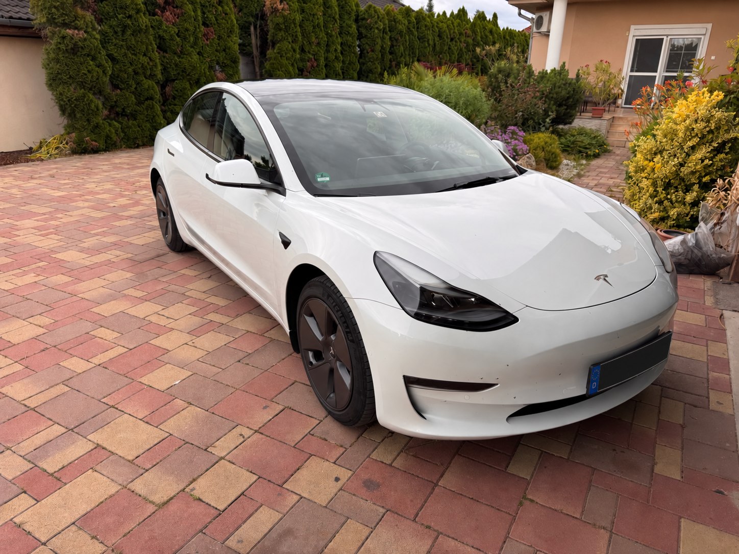 Fehér Tesla Model 3 első háromnegyedes nézetből, anonimizált rendszámmal