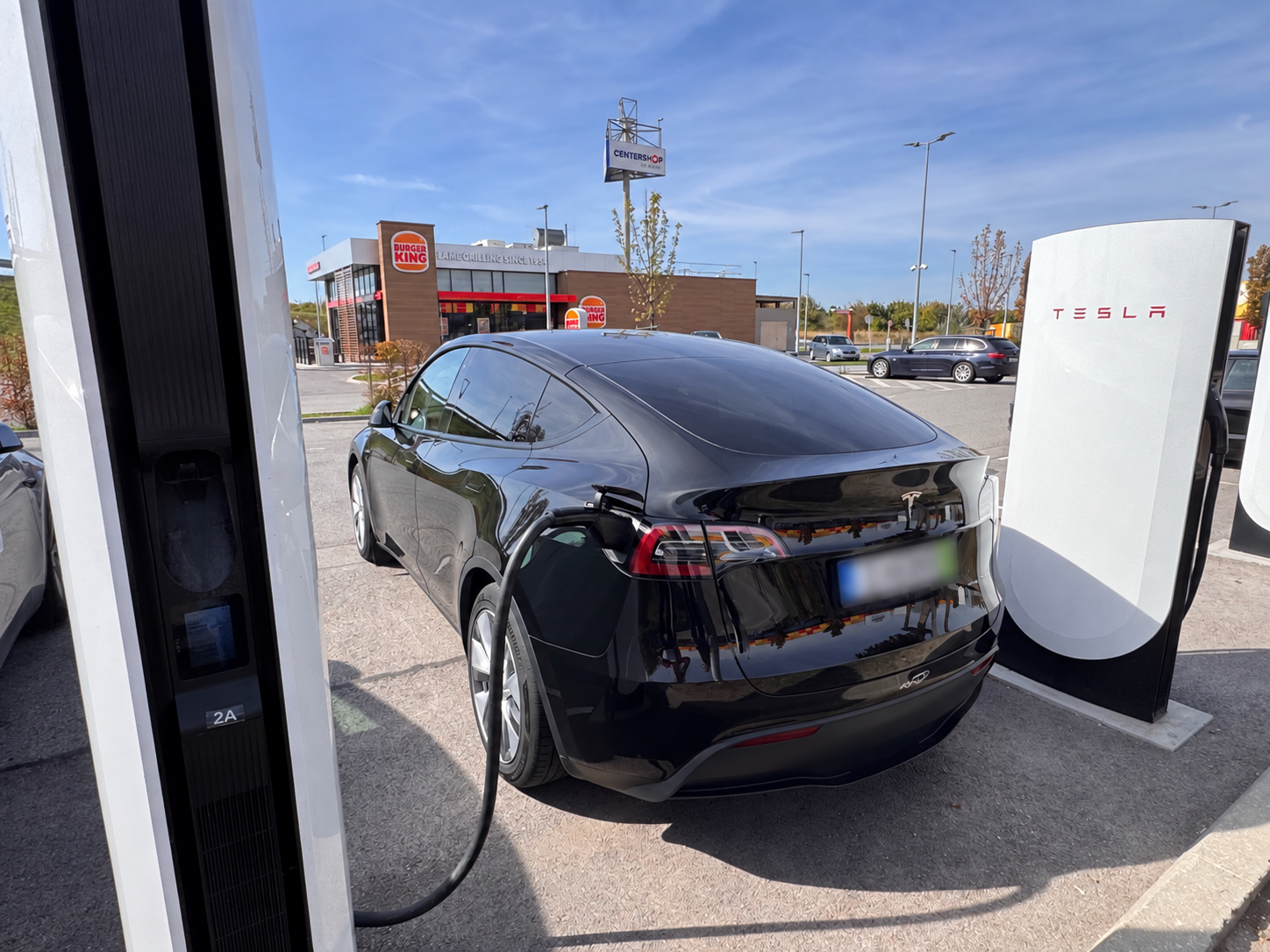Fekete Tesla töltés közben Supercharger állomáson